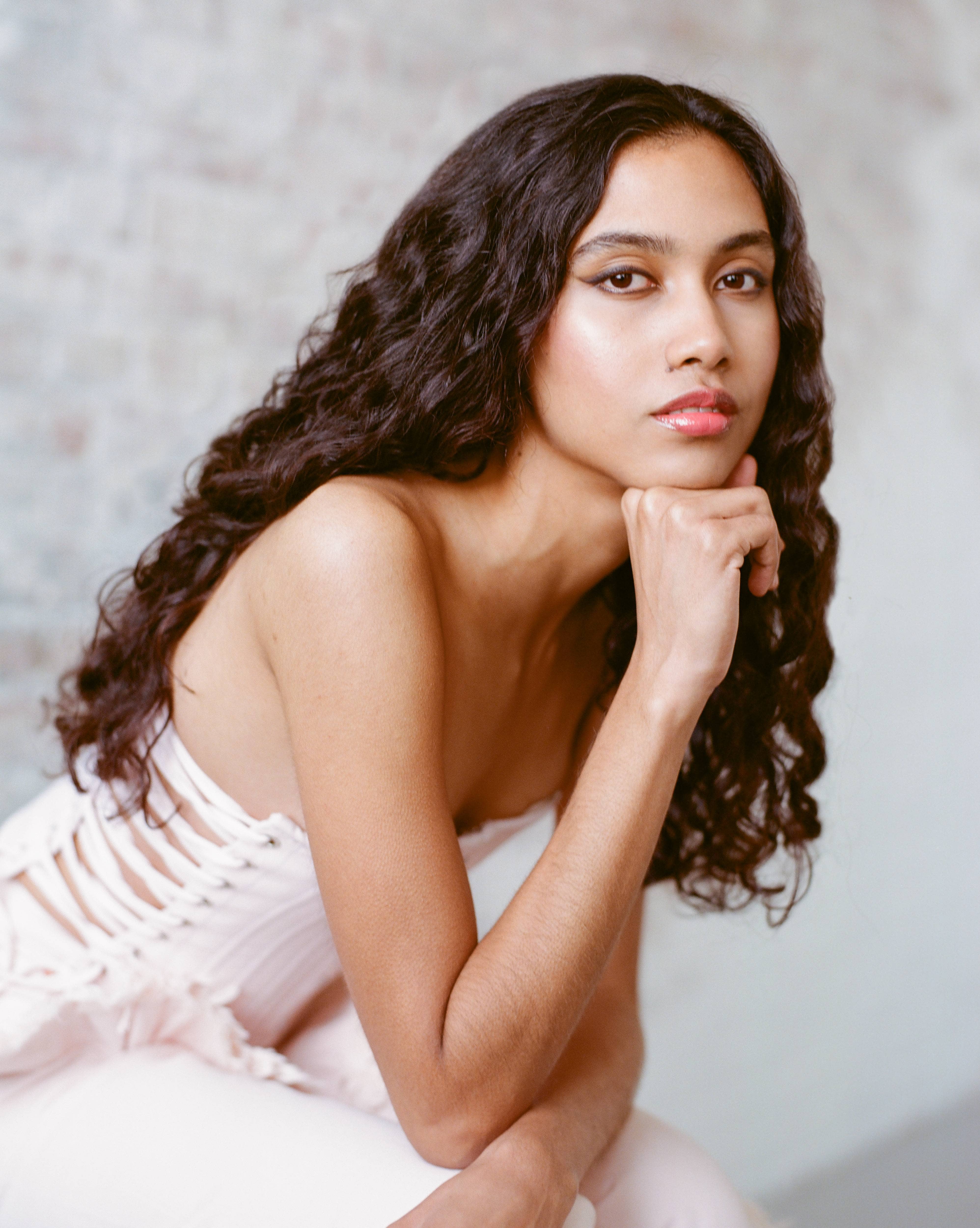 Woman with dark curly hair in white dress