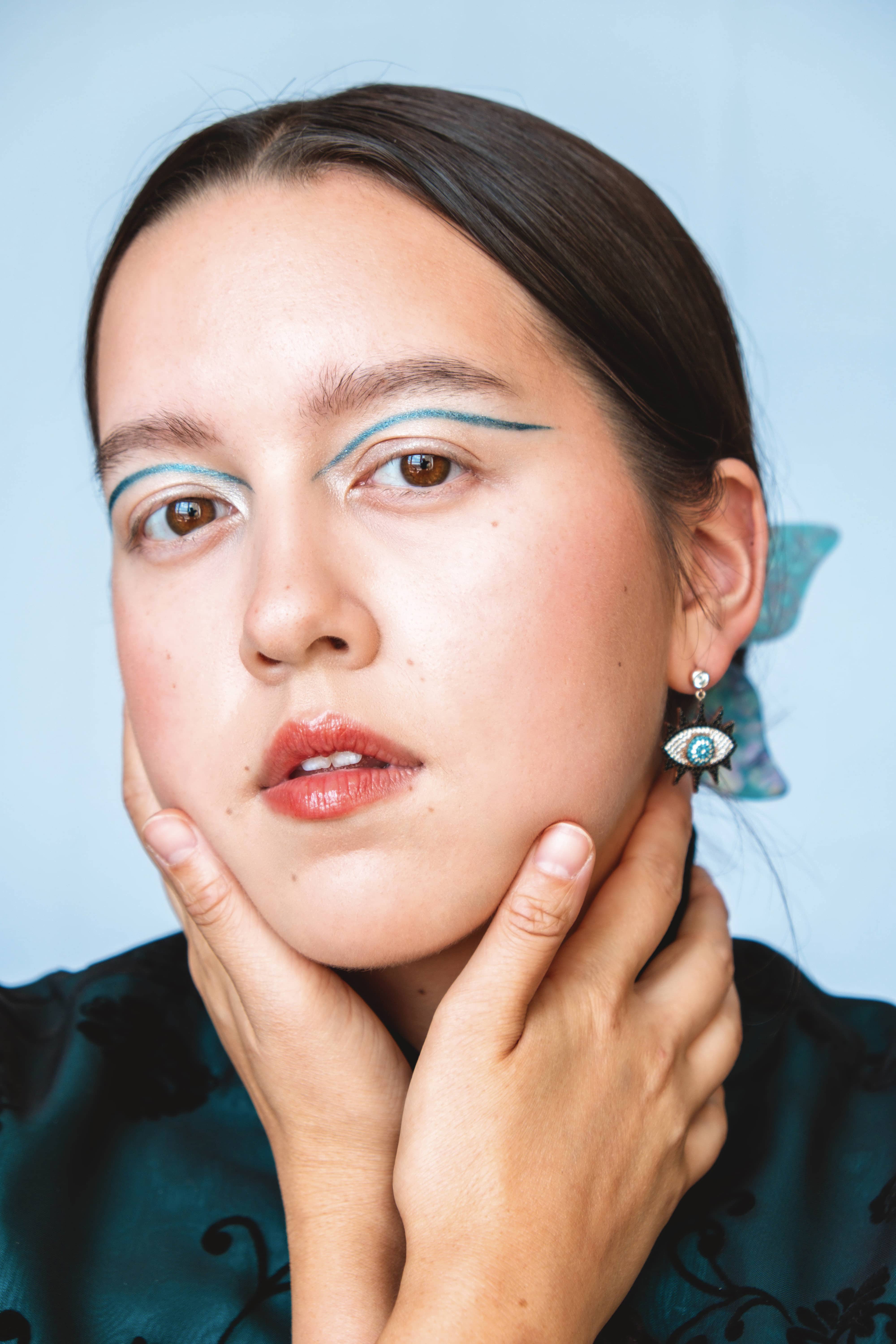 Woman with tightly-tied hair and blue makeup