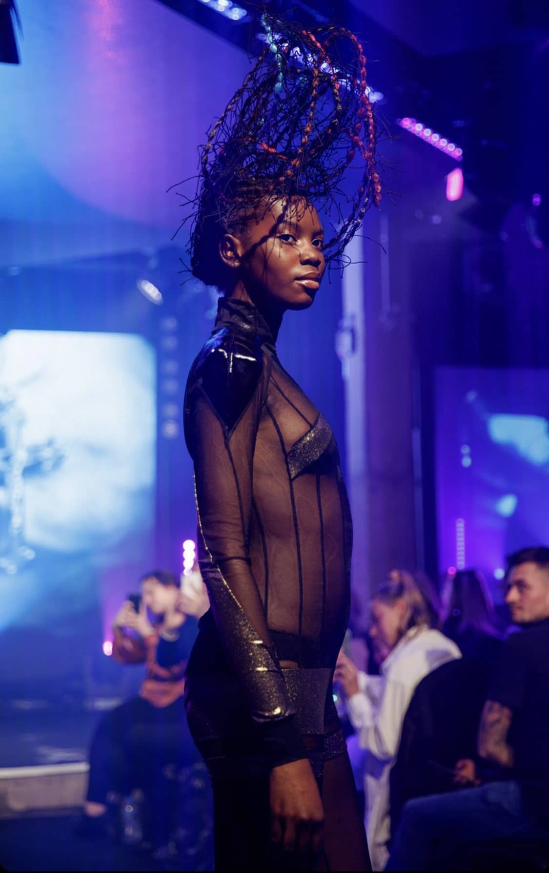 Woman in mesh-clothes with hair suspended upwards at a fashion show
