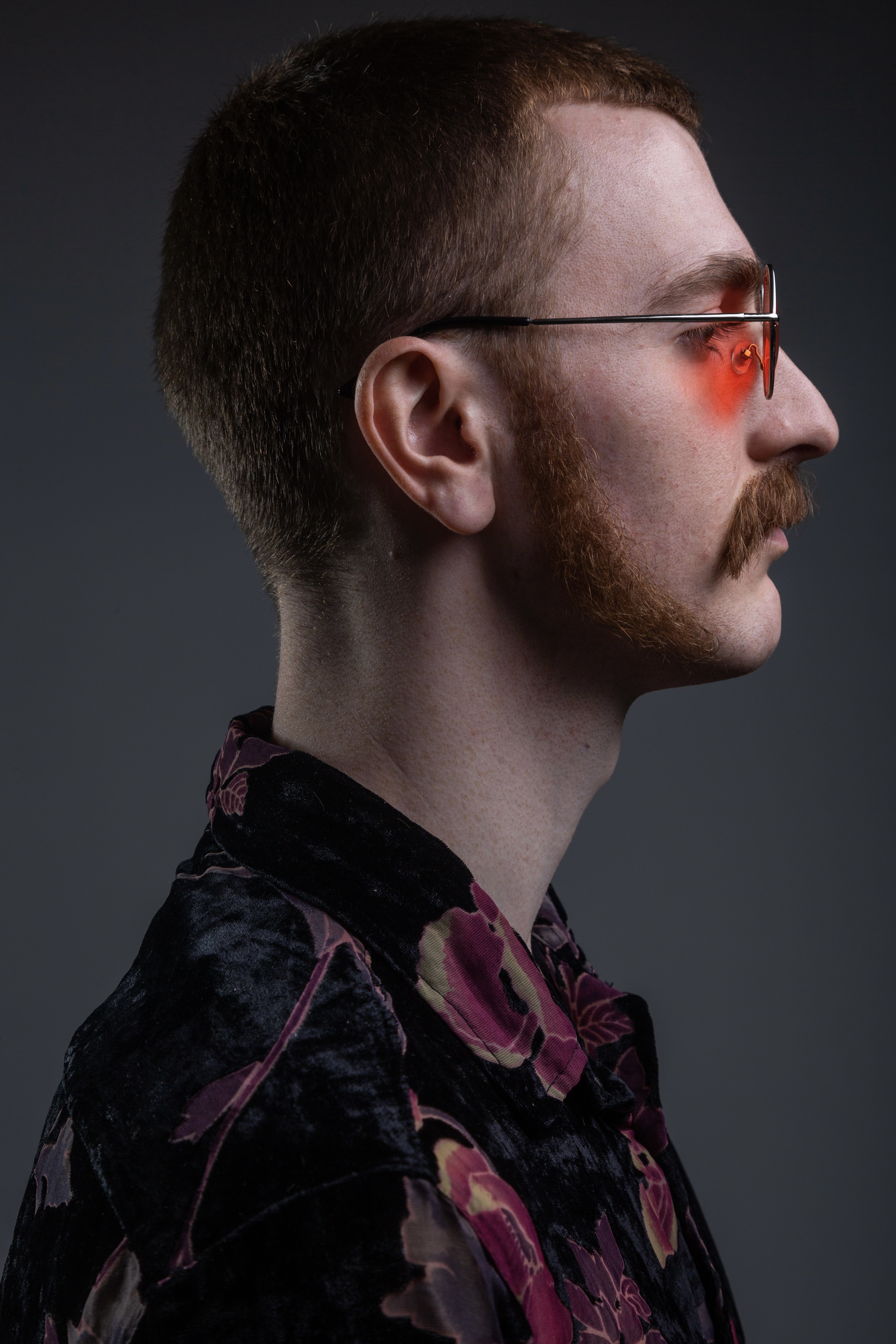 Man with facial postiche (sideburns and moustache) and retro glasses side-view