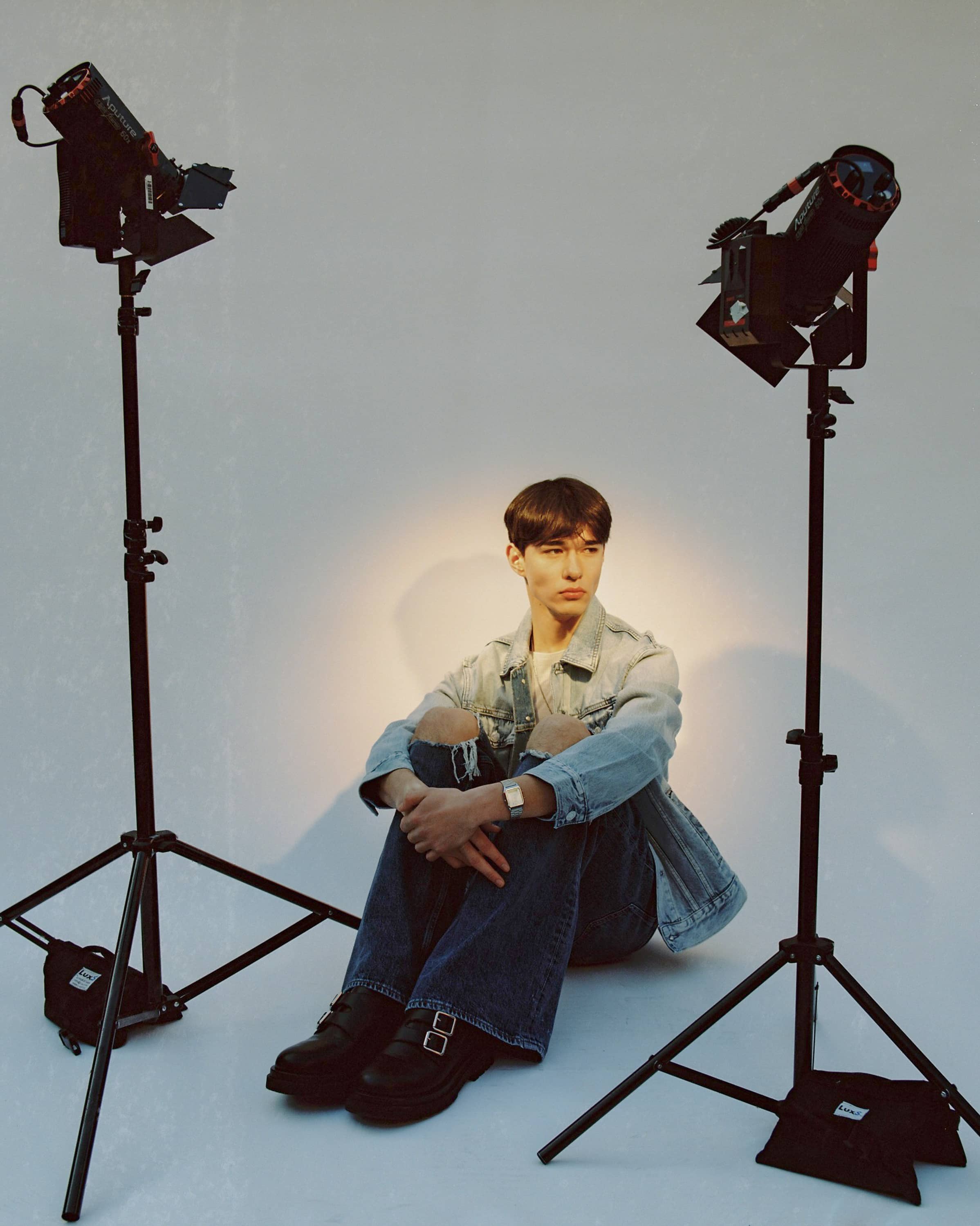 Man in denim with short hair sitting on the floor for a photo shoot