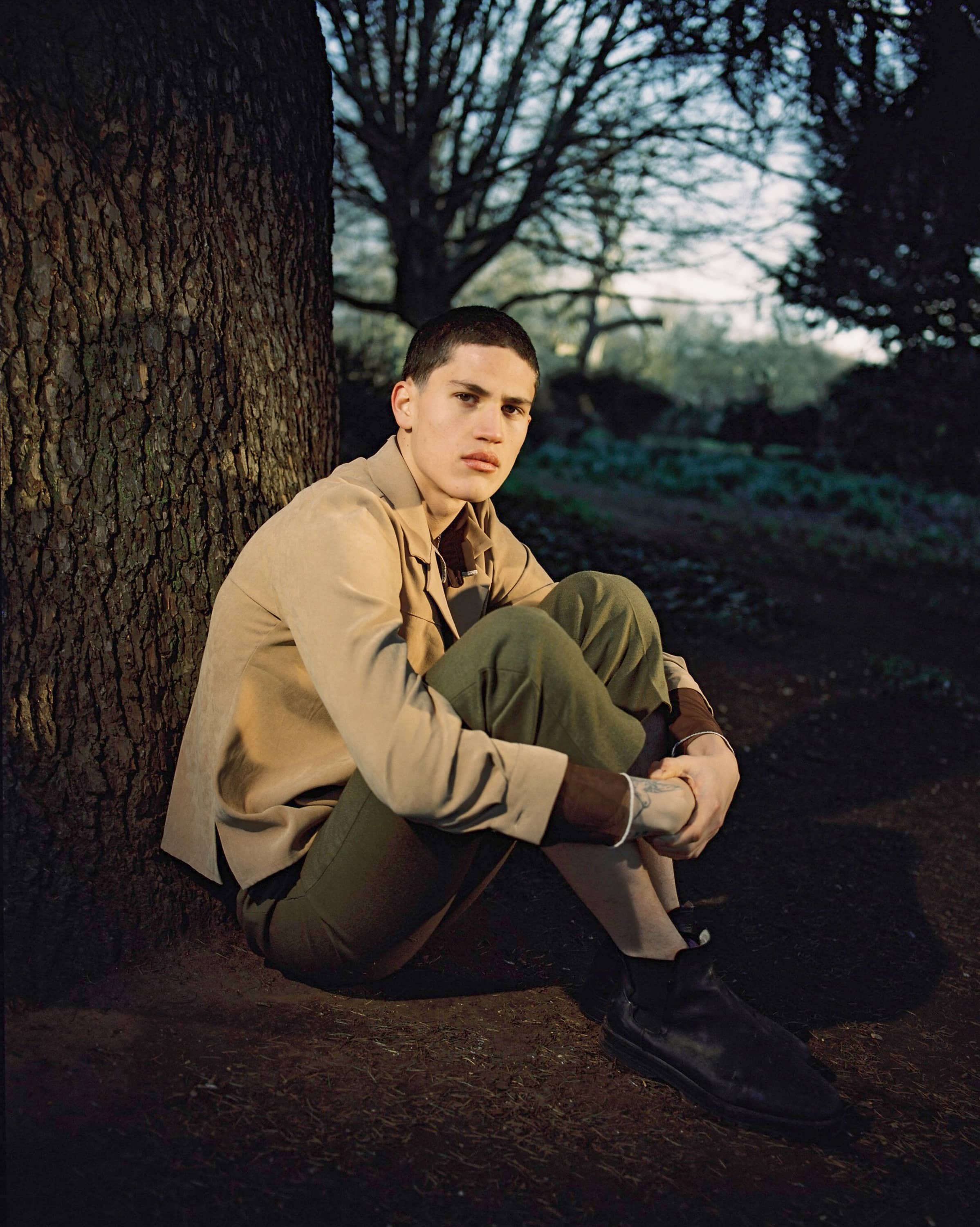 Man sitting on the floor next to a large tree